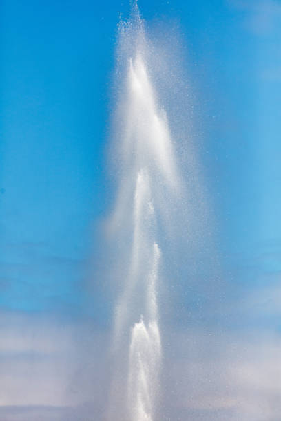 Water splashes from a fountain against a blue sky.