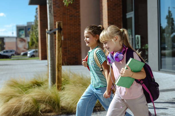 istock Two young girls happily walking to school with backpacks 2175585252
