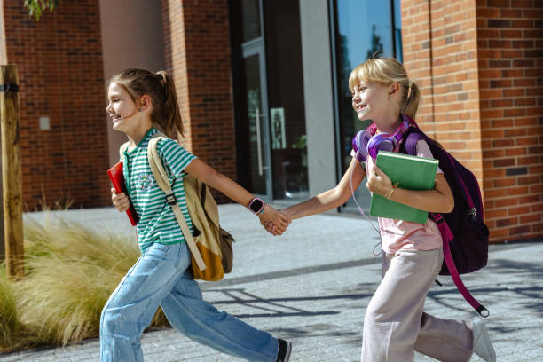 istock Happy schoolchildren holding hands and running outside school 2175585272