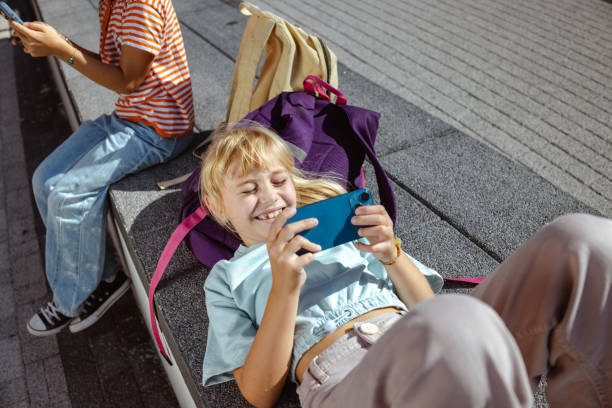 Cute girl relaxing outdoors while using smartphone after school
