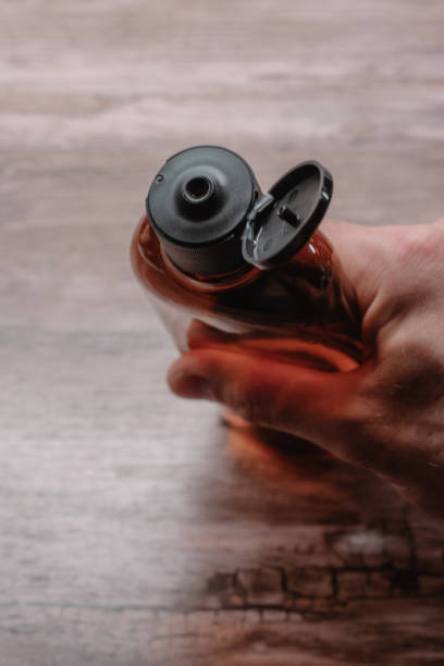 istock Male Hand Squeezing Brown Plastic Bottle with Liquid. 2175587809