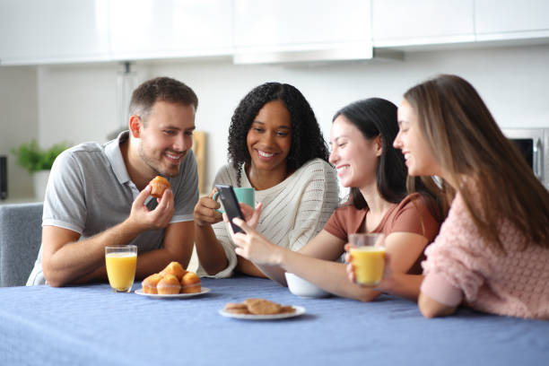 istock Happy interracial friends checking phone at breakfast in the kitchen 2175594734
