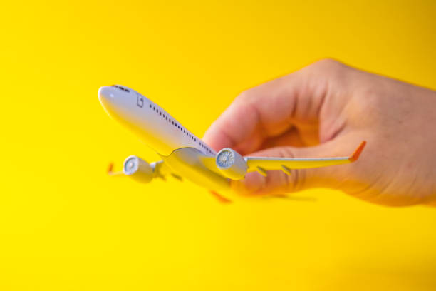 istock male hand holding an airplane yellow background 2175594780