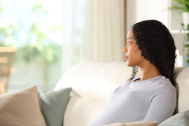 istock Distracted black woman looking through a window at home 2175594786