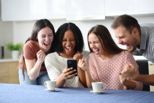 istock Excited friends celebrating success checking phone at home 2175594811