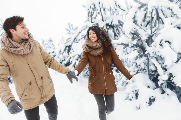 istock Smiling Girlfriend And Boyfriend Holding Hands Walking Through Winter Forest 2175595433