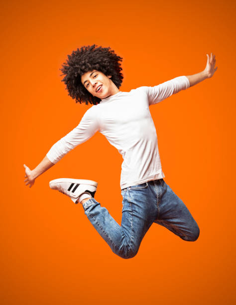 istock Modern hip-hop style man jumping on orange background 2175597254