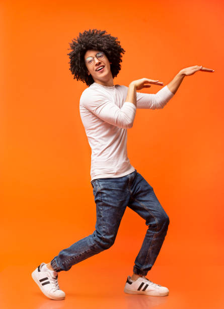 istock Funny black guy dancing in egypt style on orange background 2175597876