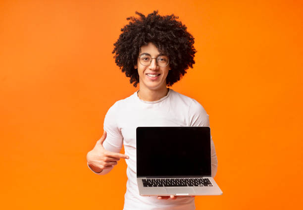 istock Smiling hipster pointing finger on blank laptop screen 2175597920