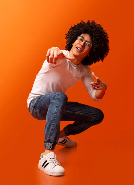 istock Cocky millennial guy pointing at camera, squatting on orange background 2175597939