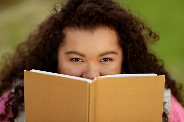 istock Young lady enjoying reading a book outdoors in bright sunlight 2175603400