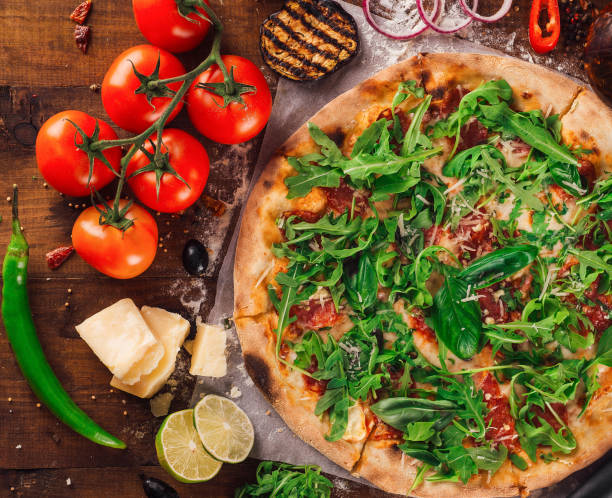 istock Freshly baked pizza lying on wooden table surrounded by ingredients 2175605273