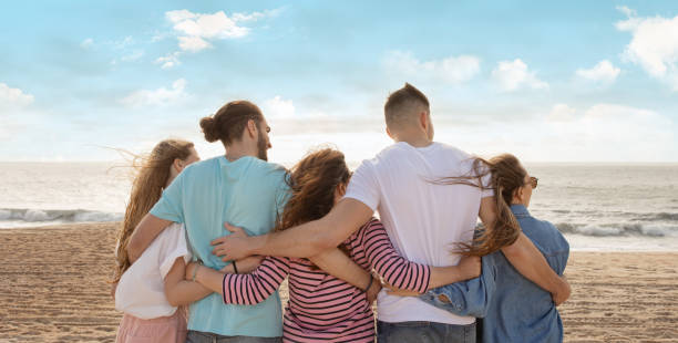 istock Friends enjoying a sunset view at the beach while embracing each other 2175607044