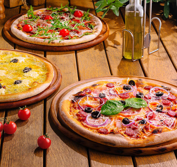istock Assorted wood-fired pizzas and wine on rustic wooden table 2175607562