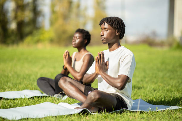 istock Two individuals practicing meditation on yoga mats in a sunny park 2175607807