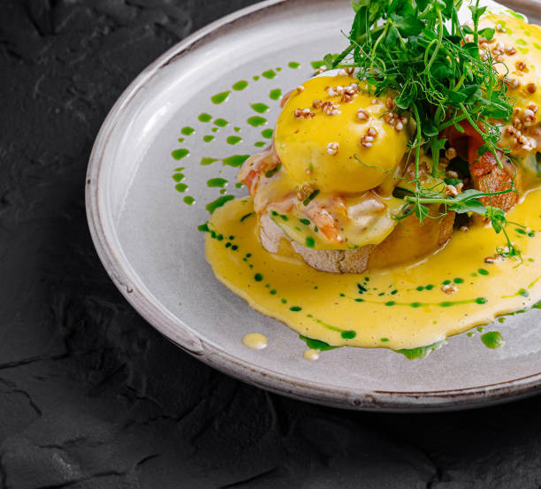 istock Delicious eggs benedict with salmon on toasted bread with microgreens on dark background 2175608465