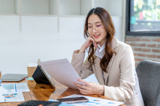 istock Happy young business woman working on her project at the office, checking data on her tablet and printed notes 2175609217