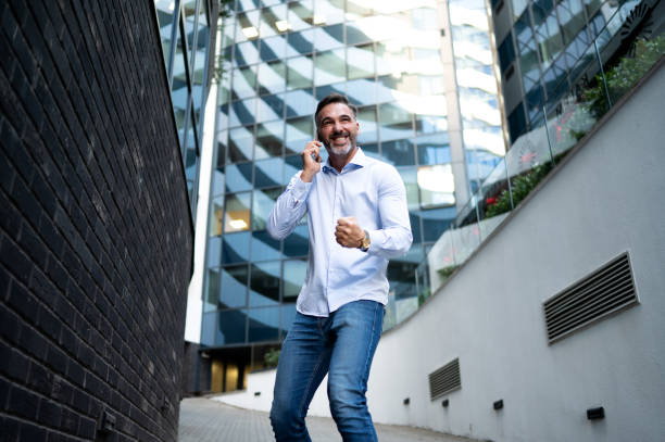 istock Mid adult male using his phone form conversation while walking through business district 2175610784