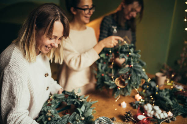 istock Happy women making Christmas wreath using natural pine branches and festive decorations. 2175610808