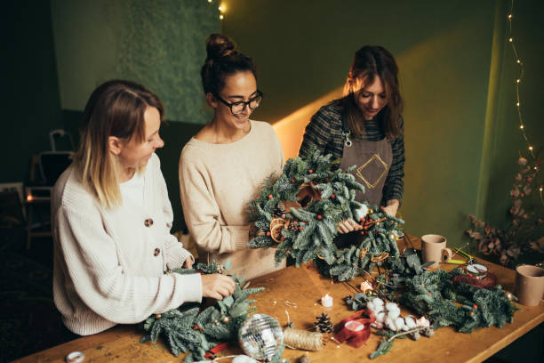 istock Happy women making Christmas wreath using natural pine branches and festive decorations. 2175610813