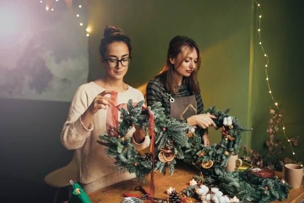 istock Happy women making Christmas wreath using natural pine branches and festive decorations. 2175610817