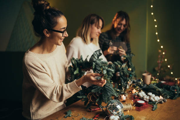 istock Happy women making Christmas wreath using natural pine branches and festive decorations. 2175610819