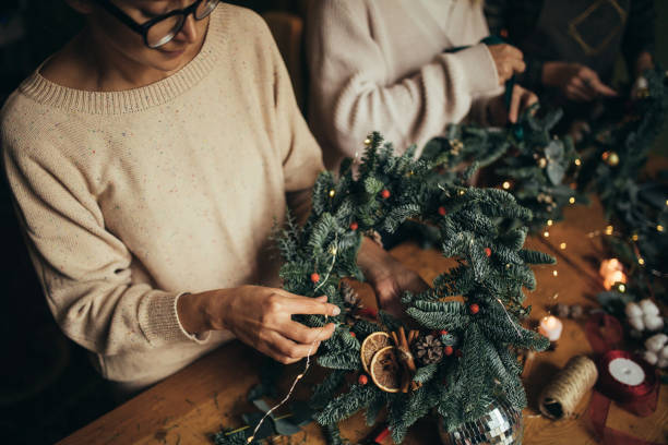 istock Happy women making Christmas wreath using natural pine branches and festive decorations. 2175611530