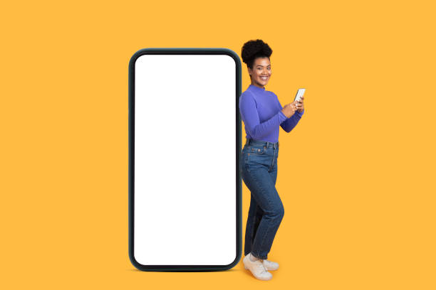 istock Young woman smiling with a smartphone on a bright yellow background 2175614096