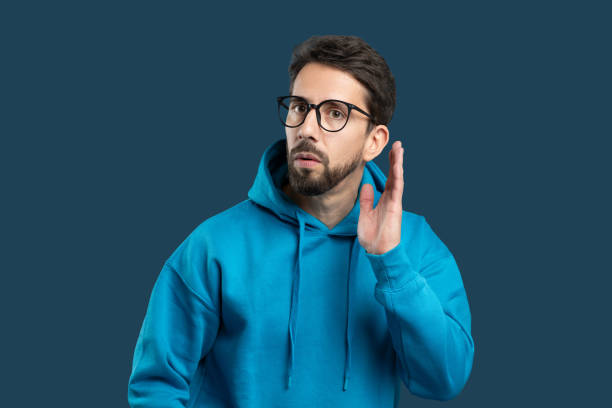 istock Man in blue hoodie attentively listening against a solid dark background 2175614836