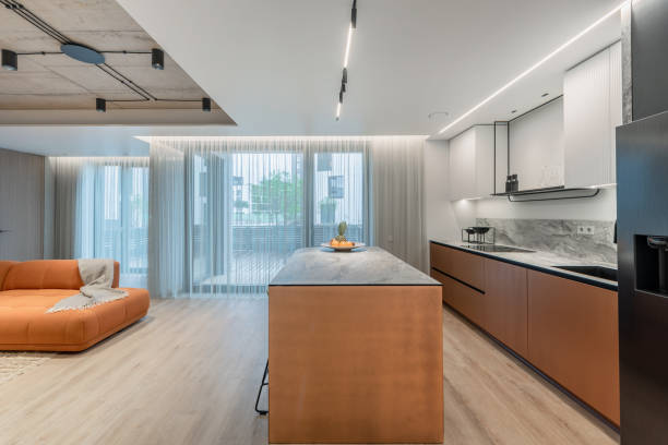 istock Scandinavian Style Cozy Modern Open Bright Kitchen Home Interior. Oven, Faucet, Fridge and Furniture in Background. Fruits on the Table. Cabinets. Windows and Curtains on the Right 2175615846