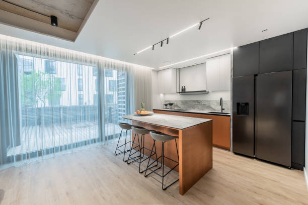 Scandinavian Style Cozy Modern Open Bright Kitchen Home Interior. Oven, Faucet, Fridge and Furniture in Background. Fruits on the Table. Cabinets. Windows and Curtains on the Right