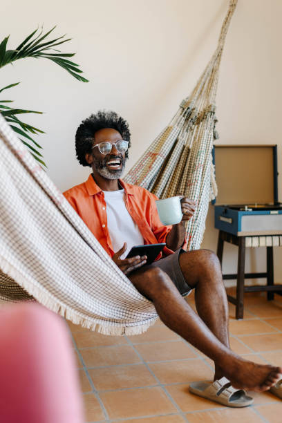 istock Mature black man relaxing in a hammock with a tablet and hot coffee 2175627592