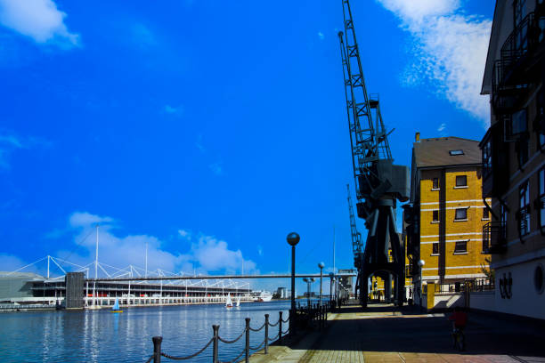 September 30th. 2024. London Docklands the rebuilt Royal Victoria Dock on a sunny day. Showing the old docks infrastructure which has been left in place. Showing the old cranes left in place.