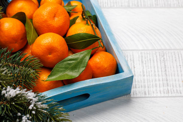 A top view of a semi-full wood crate of ripe oranges.