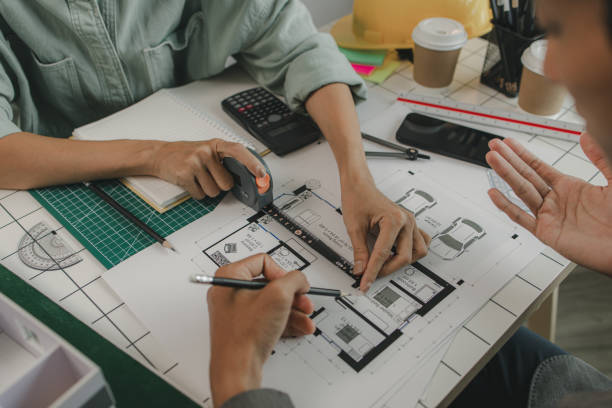 istock engineers are sitting discussing a construction plan that needs to be revised to make the structure stronger, an architect and assistant are brainstorming and examining the blueprints 2175637955