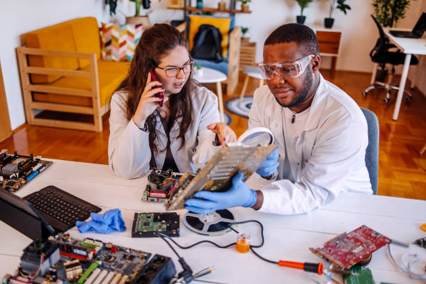 istock University students working together on project at home using electronic parts for making a computer and asking for support using mobile phone 2175640538