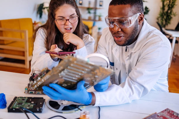 istock University students working together on project at home using electronic parts for making a computer and asking for support using mobile phone 2175640619