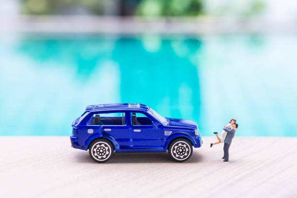 Miniature couple with blue car over blurred swimming pool background, outdoor day light