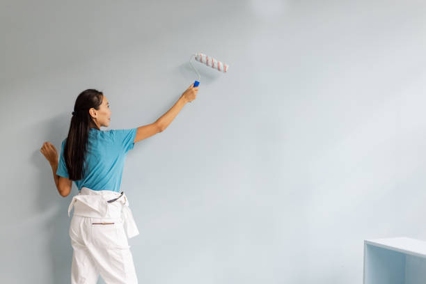 istock Focused woman painting a wall with a roller brush. 2175651759