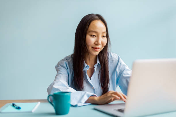 istock Focused woman types on laptop with turquoise coffee mug. 2175652015