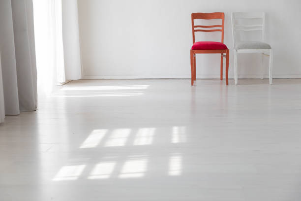 two chairs in the interior of an empty white room with a window
