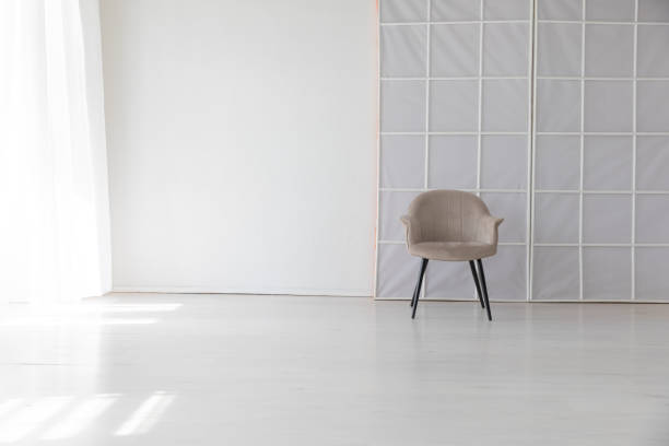 Gray chair in the interior of an empty white room with a window