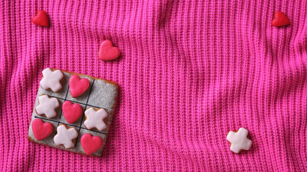 istock Vibrant pink wallpaper with a gingerbread tic-tac-toe game on a cozy knitted sweater backdrop. Valentine's Day Conception. Romantic Background 2175653901