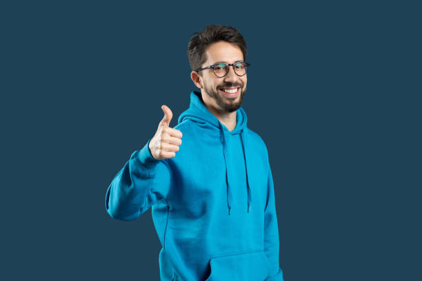 istock A young man with glasses and a beard smiles warmly while giving a thumbs-up 2175654738