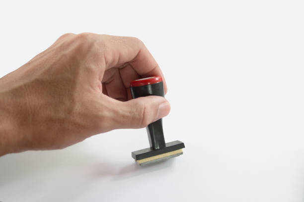 The Asian hand holding rubber stamp on white paper background.