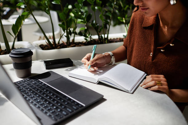 istock Businesswoman Writing in Notebook while Working or Studying at Table in Cafe 2175655035