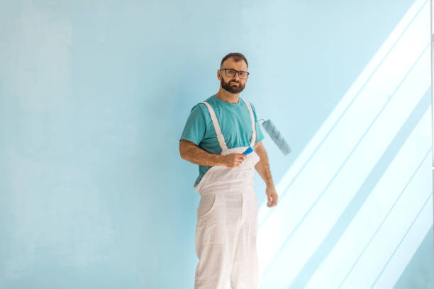 istock Man in white overalls holding paint roller with ease 2175656680