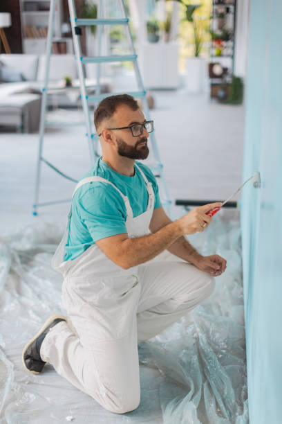 istock Man painting a wall with turquoise paint in a room 2175658407