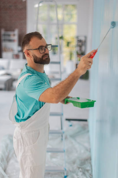 istock Man painting blue wall with roller and paint tray. 2175658535