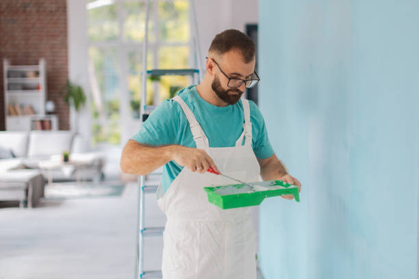 istock Man with tray applying blue paint to wall surface 2175660574